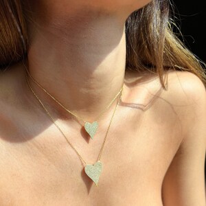 May include: Two gold necklaces with heart-shaped pendants. Both pendants are covered in small, clear stones.