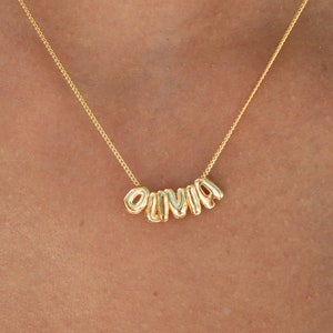 May include: A gold chain necklace with the name "Olivia" spelled out in gold letters.