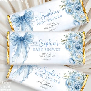 Può includere: Tre confezioni di barrette di cioccolato a tema baby shower. Ogni confezione presenta un fiocco azzurro, decorazioni floreali e la scritta "Sophia's BABY SHOWER THANKS FOR COMING!" in elegante corsivo. Le confezioni hanno bordi dorati.