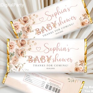 Op de afbeelding: Een printbaar ontwerp voor een chocoladeverpakking met een bloemenpatroon en de tekst "Sophia's Baby Shower" en "Bedankt voor je komst!" in roze en gouden letters. De verpakking bevat ook de datum "05.05.20XX".