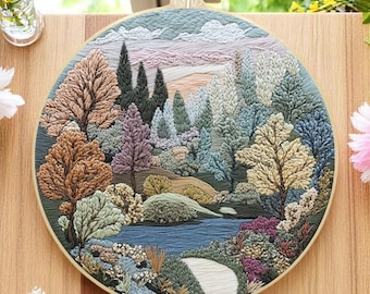 May include: Embroidered hoop art depicting a forest scene with a river winding through it. The trees are a variety of greens, browns, and yellows, and the river is a deep blue. The background is a soft pink and blue sky.