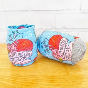 May include: Two blue and white fabric yarn bowl covers with a red and orange yarn ball, knitting needles, and the text "Knit to Live Live to Knit".