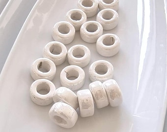 Könnte beinhalten: Eine Sammlung weißer Keramik-Donut-Perlen, perfekt für die Schmuckherstellung oder Bastelprojekte.