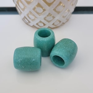 Puede incluir: Tres scrunchies para el pelo de cerámica azul turquesa con un acabado craquelado.