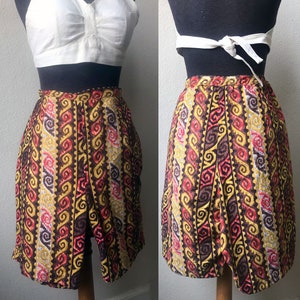 May include: A white halter top with a brown, red, and yellow patterned skirt. The skirt has a geometric design with swirls and lines.