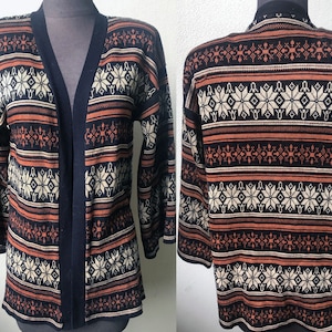 May include: A black, brown, and white patterned cardigan with a long sleeve and a v-neck.