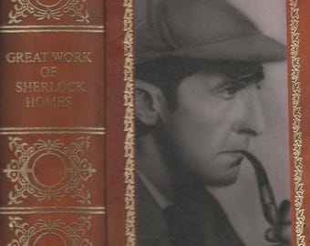May include: A vintage book cover with a red leather spine and gold accents. The title "Great Work of Sherlock Holmes" is printed on the spine. The front cover features a black and white photo of a man wearing a hat and smoking a pipe.