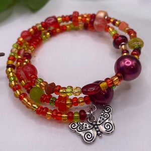 May include: Multi-strand bracelet featuring red, orange, yellow and green beads, a large burgundy bead and a silver butterfly charm.