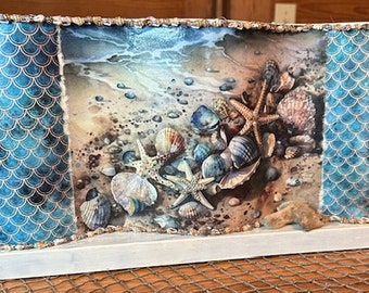 May include: A lampshade with a blue and gold mermaid scale pattern on the sides. The front of the lampshade features a watercolor painting of seashells and starfish on a sandy beach.