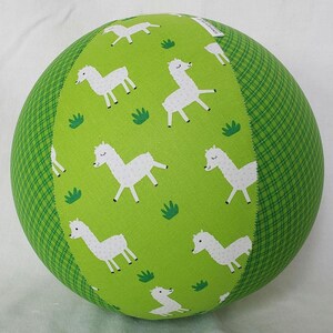 May include: A green and white ball with a pattern of llamas and grass. The ball is half green with a plaid pattern and half green with a llama pattern.