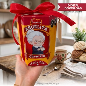 Pode incluir: Uma caixa de presente hexagonal vermelha e amarela com uma ilustração de desenho animado de uma idosa de cabelos brancos e óculos segurando uma xícara, com o texto Te quiero ABUELITA Chentita Feliz Día, com um grande laço vermelho.