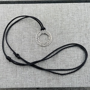 A silver Celtic knot pendant necklace with a black cord.