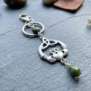 Puede incluir: Llavero Claddagh plateado con una cuenta de piedra preciosa verde y un colgante en forma de lágrima. El diseño Claddagh presenta un corazón, una corona y manos, que simbolizan el amor, la lealtad y la amistad. El llavero tiene un cierre de mosquetón.