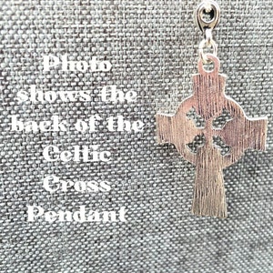 The back of a silver Celtic cross pendant. The pendant has a detailed design with intricate knots and a loop at the top for attaching a chain.