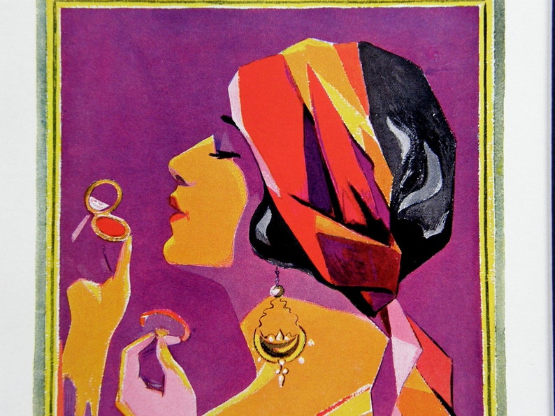 May include: A woman with a red, orange, and black turban is applying makeup with a compact mirror. She is wearing a gold earring and a purple and orange outfit.