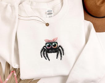 Sudadera de araña saltarina, adorable jersey de araña con cuello redondo, regalo único para amantes de los insectos, suéter minimalista de araña con lazo rosa, regalo para amantes de las arañas saltarinas.