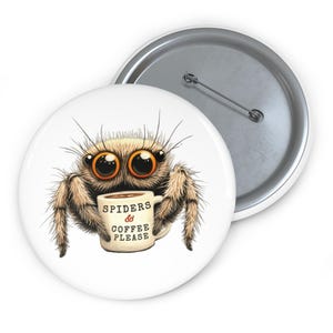 Op de afbeelding: Een witte button met een cartoon spin met grote oranje ogen en een harige lijf. De spin houdt een koffiemok vast met de tekst "Spiders & Coffee Please". De button heeft een zilveren speld aan de achterkant.