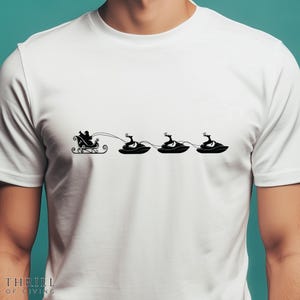 May include: White t-shirt with a black graphic of Santa's sleigh pulled by three reindeer on jet skis. The text "THRILL OF GIVING" is printed at the bottom of the shirt.