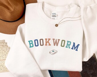 May include: White sweatshirt with the text "BOOKWORM" in colorful letters. A small illustration of a book with a heart on it is below the text.