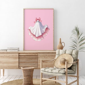 May include: A white ghost with a pink bow and pink ruffled trim on a pink background.