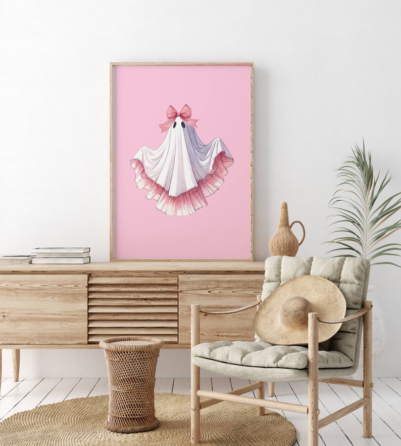 May include: A white ghost with a pink bow and pink ruffled trim on a pink background.