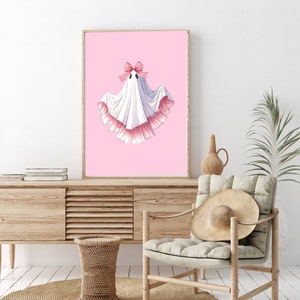 May include: A white ghost with a pink bow and pink ruffled trim on a pink background.