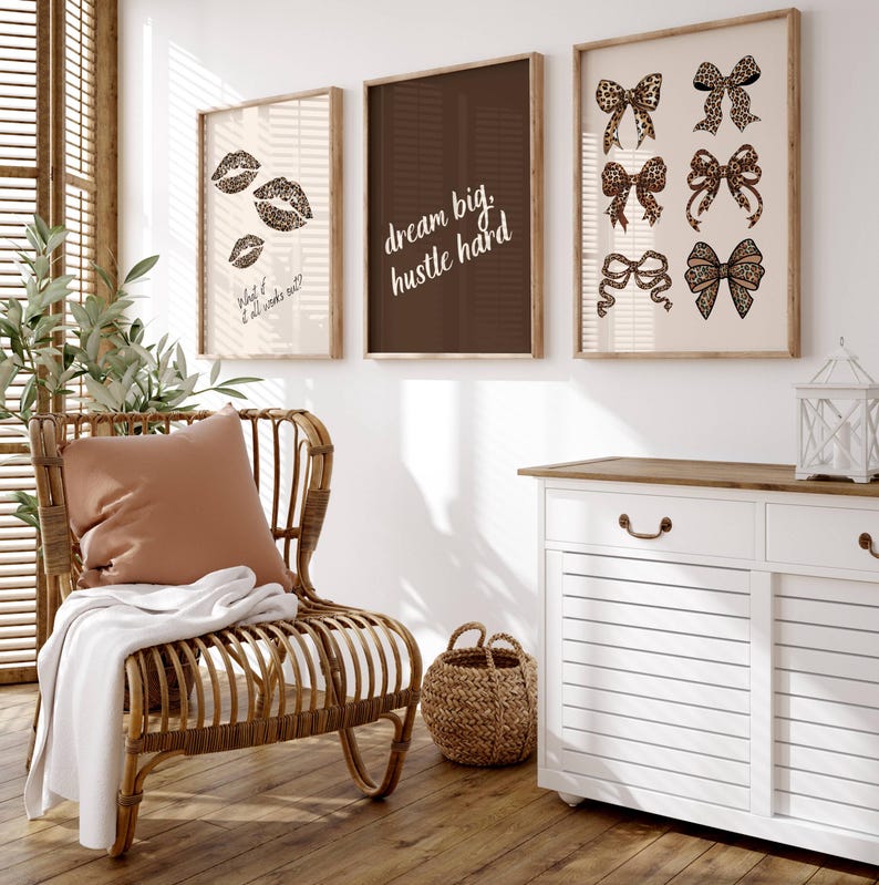 Puede incluir: Tres impresiones enmarcadas con citas inspiradoras y dise&ntilde;os de estampado de leopardo. Las impresiones est&aacute;n colgadas en una pared blanca sobre un armario blanco con una tapa de madera. Una silla de mimbre con un coj&iacute;n marr&oacute;n se encuentra frente al armario.