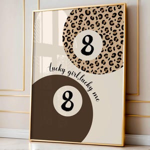 Puede incluir: Una impresi&oacute;n abstracta beige y marr&oacute;n con dos dise&ntilde;os de bolas de billar n&uacute;mero 8. La bola de arriba est&aacute; sobre un fondo de estampado de leopardo. La bola de abajo est&aacute; sobre un fondo marr&oacute;n. El texto "lucky girl, lucky me" est&aacute; escrito en cursiva negra.