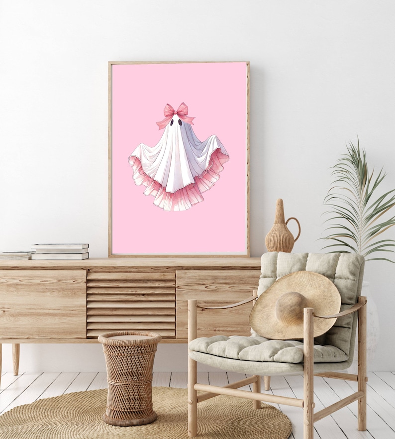 May include: A white ghost with a pink bow and pink ruffled trim on a pink background.