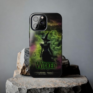 May include: Black iPhone case featuring a green and black image of a witch wearing a pointed hat, with the word "WICKED" in green lettering.