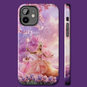Puede incluir: Funda de teléfono con una ilustración de fantasía de una mujer con un vestido rosa sosteniendo una varita mágica, un hada y flores rosas. La funda tiene un acabado brillante y una combinación de colores morado y rosa. El lateral de la funda también tiene un diseño floral a juego.