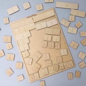 Op de afbeelding: Houten fractie leerset met een houten bord en meerdere fractie stukken. Het bord heeft een liniaal en uitsparingen voor fracties. De stukken zijn gemarkeerd met fracties zoals 1/2, 1/3 en 1/4. De tekst "UsCrafting" is zichtbaar.