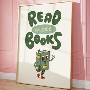 May include: A white poster with a gold frame features a green cartoon book character with a smiling face and the text "READ MORE BOOKS" in green letters.