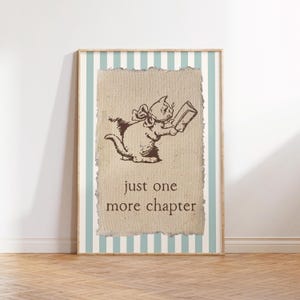 May include: A framed print featuring a sepia-toned illustration of a cat reading a book. The cat has a bow and is holding a book. The text "just one more chapter" is below the cat. The frame has a light blue and white striped background.