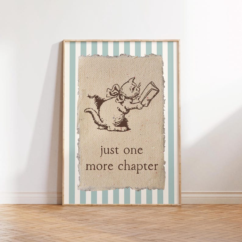 May include: A framed print featuring a sepia-toned illustration of a cat reading a book. The cat has a bow and is holding a book. The text "just one more chapter" is below the cat. The frame has a light blue and white striped background.