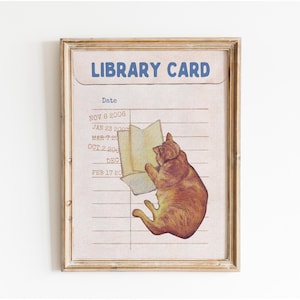 Puede incluir: Una impresión enmarcada de una tarjeta de biblioteca con un gato de dibujos animados leyendo un libro. La tarjeta tiene una sección de fecha con fechas de 2000 a 2006.