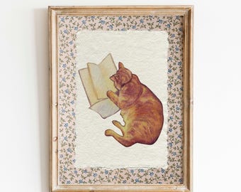 May include: A framed watercolor painting of an orange tabby cat reading a book. The cat is lying on its side with its head resting on the book. The background is a light cream color with a floral pattern border.
