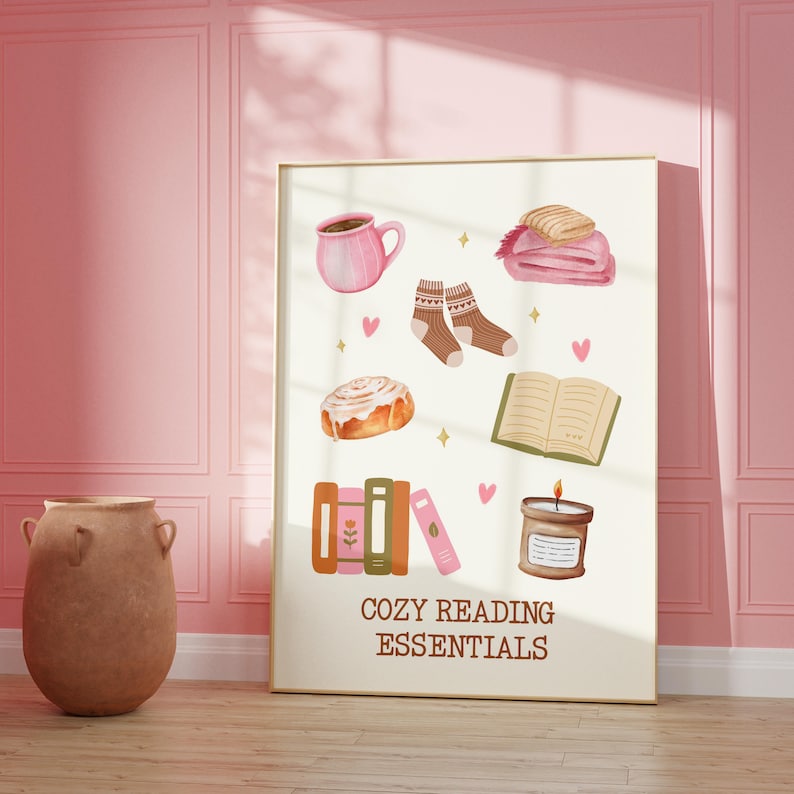 May include: A white poster with the text "Cozy Reading Essentials" in brown lettering. The poster features illustrations of a cup of coffee, a book, a candle, a cinnamon roll, a pair of socks, and a blanket.