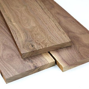 May include: Three rectangular wooden planks with a natural wood grain pattern. The planks are various sizes and are a warm brown color. The wood has a smooth, finished appearance, suitable for woodworking projects.