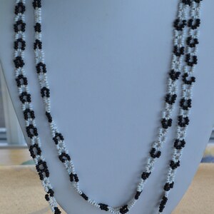Peut inclure: Un collier à double rang de perles noires et blanches. Les perles sont disposées en un motif de petits cercles.