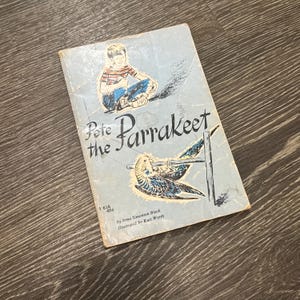 Puede incluir: Libro infantil vintage titulado "Pete the Parrakeet" con una cubierta azul claro. La portada presenta una ilustración de un niño y un periquito. El libro es de Irma Simonton Black e ilustrado por Kurt Werth.