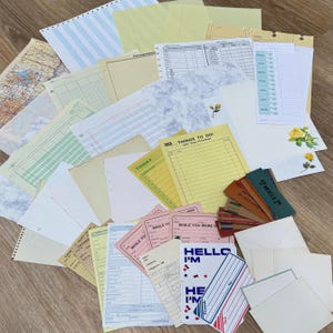 May include: A collection of vintage stationery items, including lined paper, envelopes, and index cards. The assortment features various colors, patterns, and sizes, with some pieces displaying handwritten text and floral accents. Some cards read "HELLO I'M" and "THINGS TO DO!"