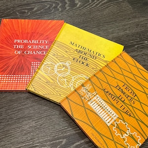 May include: Three vintage books with colorful covers. The titles include "Probability: The Science of Chance," "Mathematics Around the Clock," and "From Fingers to Computers." The covers feature graphic designs and text in white.