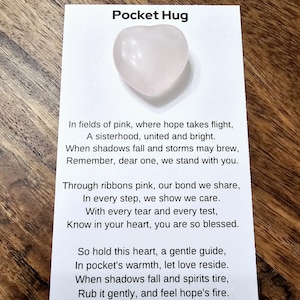 May include: A white heart-shaped crystal with the text "Pocket Hug" and a poem about sisterhood and hope. The poem includes the phrase "Remember, dear one, we stand with you."