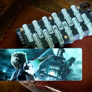 May include: A rectangular game accessory featuring a character with spiky blonde hair and a large sword, paired with a black modular tracker displaying white text labels including Indestructible, Lifelink, Deathtouch, Trample, Hexproof, Flying, Menace, Reach, Defender, Vigilance, First Strike, and Double Strike.