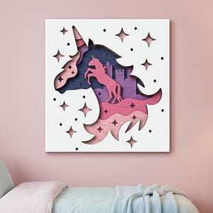 May include: A layered wooden wall art piece featuring a unicorn head silhouette with a castle and stars. The artwork uses shades of pink, purple, and blue, set against a white background. The unicorn is in a rearing pose.