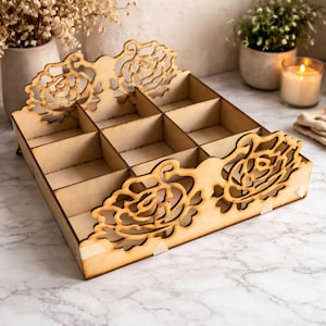 May include: A wooden organizer with a grid of twelve compartments. The sides feature decorative laser-cut floral designs. The natural wood color and intricate cutouts create a rustic, elegant aesthetic. Ideal for storing small items.