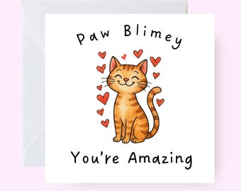 May include: A greeting card with a cartoon orange tabby cat illustration surrounded by red hearts. The card reads "Paw Blimey You're Amazing" in black text, with a white envelope.