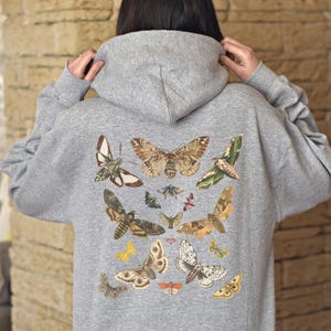 May include: A gray hooded sweatshirt with a print of various butterflies and moths in shades of brown, white, and black. The print covers the back of the sweatshirt.