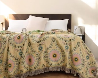 May include: A yellow throw blanket with a floral pattern in shades of pink, green, and blue. The blanket has a fringe border.